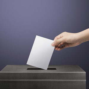 Hand holding ballot paper for election vote concept background.